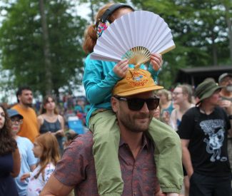 father w kid on his shoulders with a fan